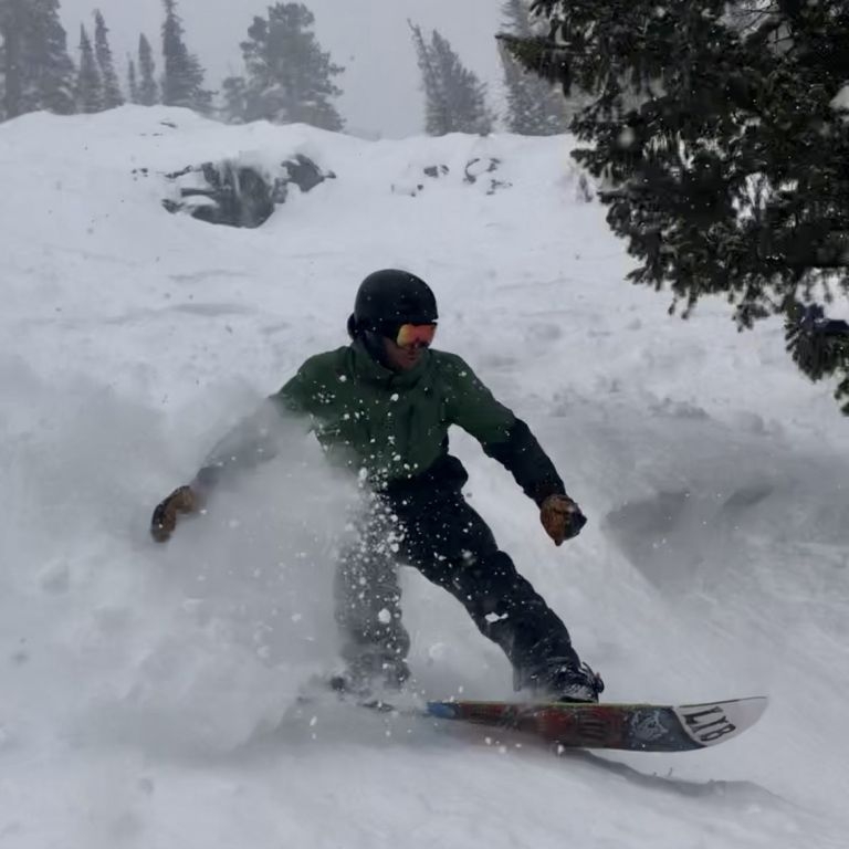 David Gates kicks up a siiick spray of snow on a snowboard
