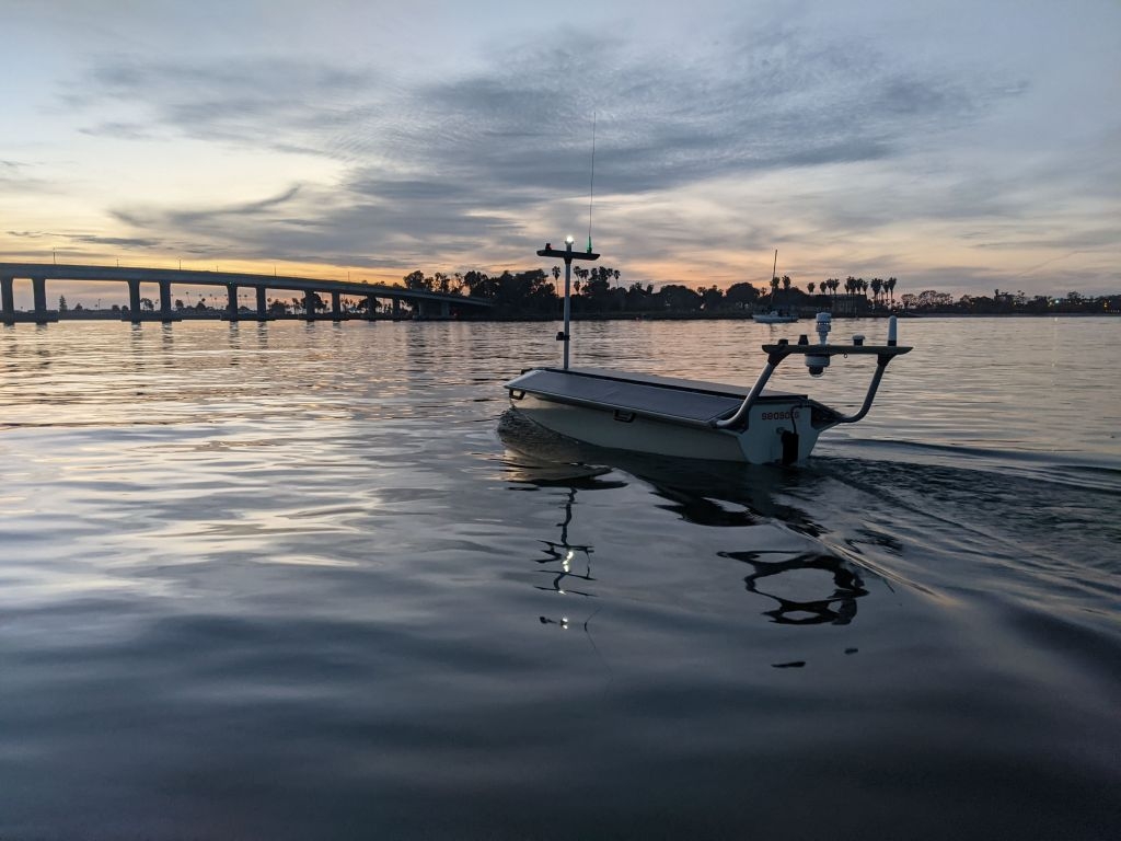 A Lightfish autonomous surface vehicle approaches a bridge at sunset